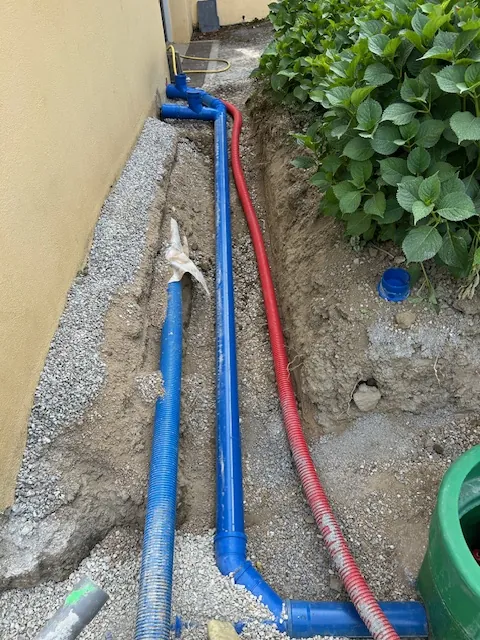 Canalisations bleues et rouges posées le long d'une maison